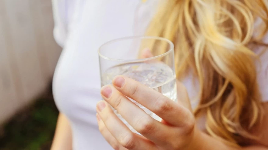 γυναίκα κρατά ένα ποτήρι νερό