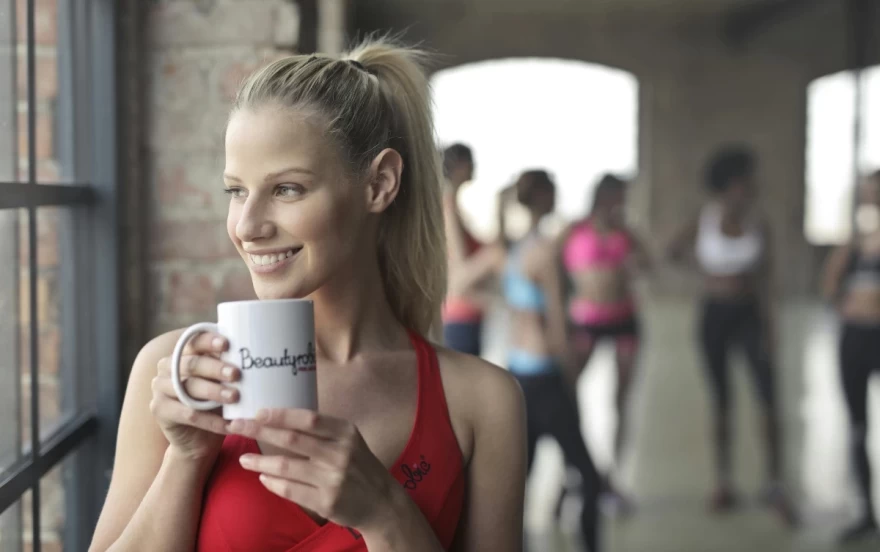 όμορφη γυναίκα πίνει καφέ στο γυμναστήριο