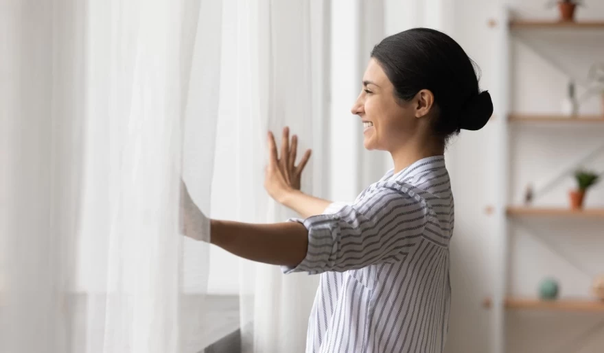 χαρούμενη γυναίκα ανοίγει το παράθυρό της