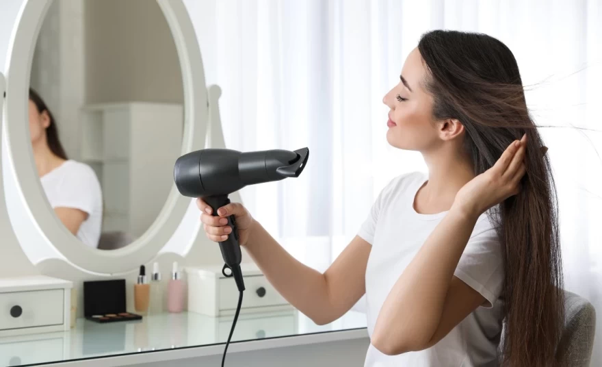 γυναίκα στεγνώνει τα μαλλιά της με σεσουάρ