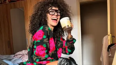 Η μαρία Σολωμού με φλοράλ πουλόβερ και καφέ στο χέρι