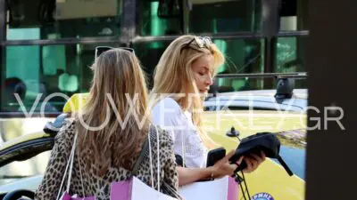 Η Μαριέττα Χρουσαλά στο κέντρο της Αθήνας κοιτώντας τα πράγματα που κρατάει στα χέρια της