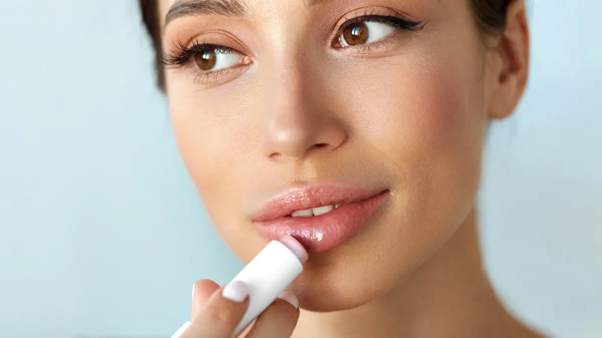 ένα κορίτσι βάζει lip gloss