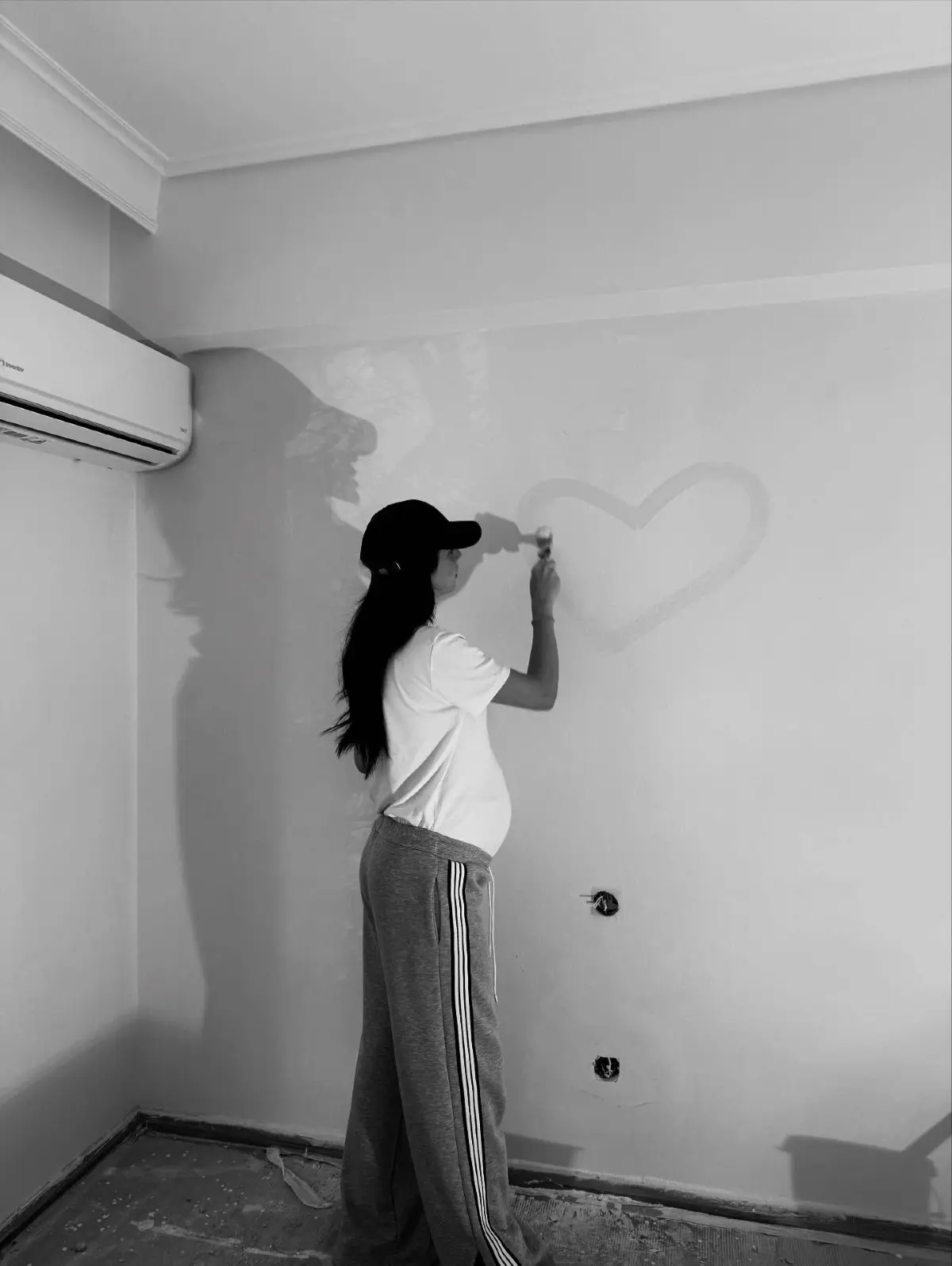 Η Βαλασία Συμιακού, σύντροφος του Νίκου Πολυδερόπουλου, ζωγραφίζει μια καρδιά στον τοίχο του βρεφικού δωματίου, στο σπίτι του ζευγαριού.