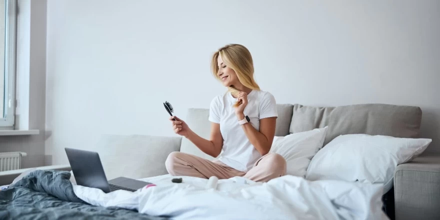 γυναίκα χτενίζεται πάνω στο κρεβάτι