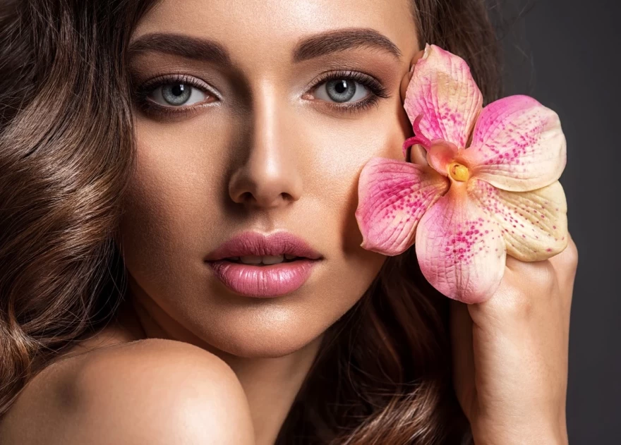 γυναίκα μακιγιαρισμένη κρατά λουλούδι