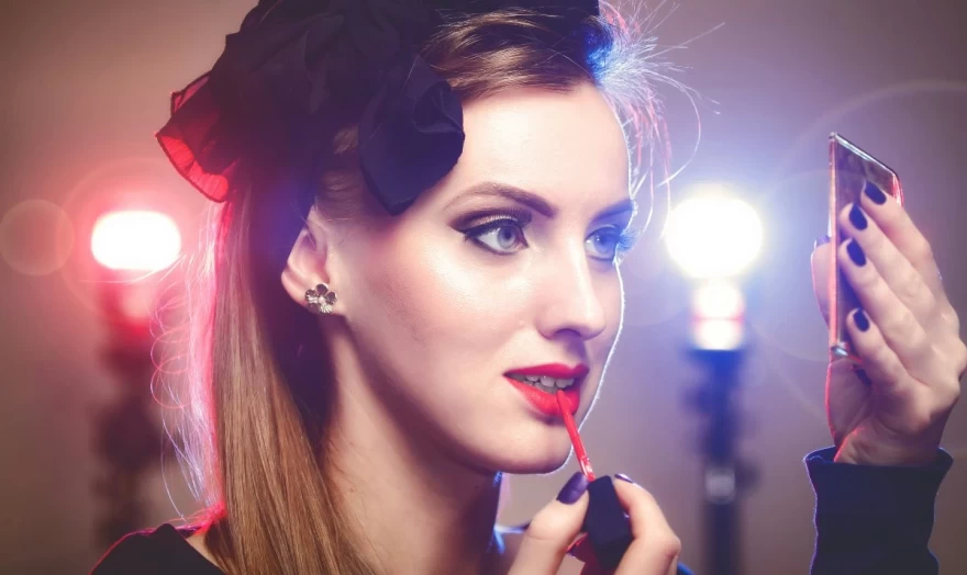 κοπέλα εφαρμόζει κόκκινο κραγιόν στα χείλη