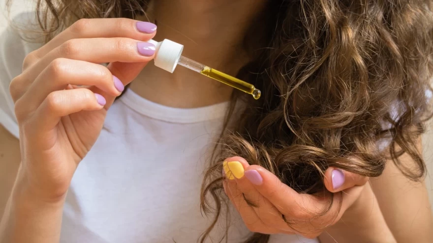 γυναίκα εφαρμόζει έλαιο μαλλιών