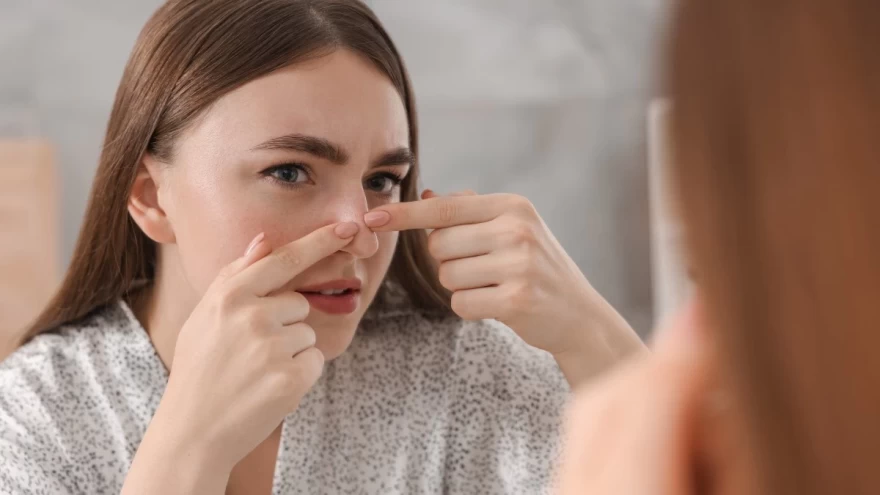 γυναίκα πειράζει ακουμπά σπυράκι πάνω στη μύτη