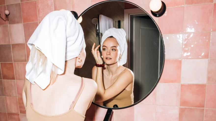 γυναίκα φροντίζει την επιδερμίδα της μπροστά στον καθρέφτη