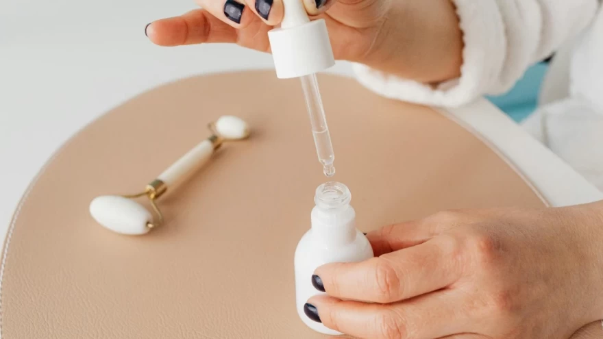 γυναίκα εφαρμόζει σέρουμ μέσα από ένα μπουκάλι
