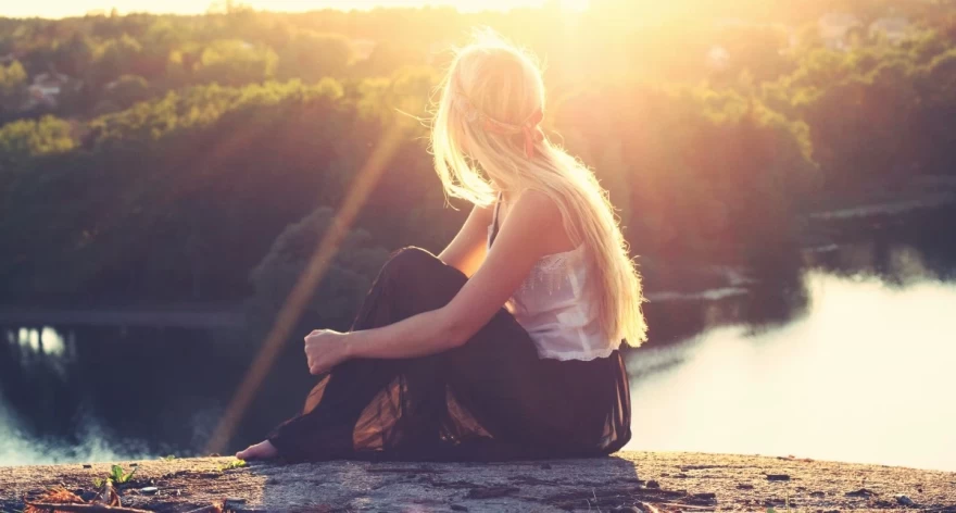 κορίτσι κάθεται και ατενίζει μια λίμνη