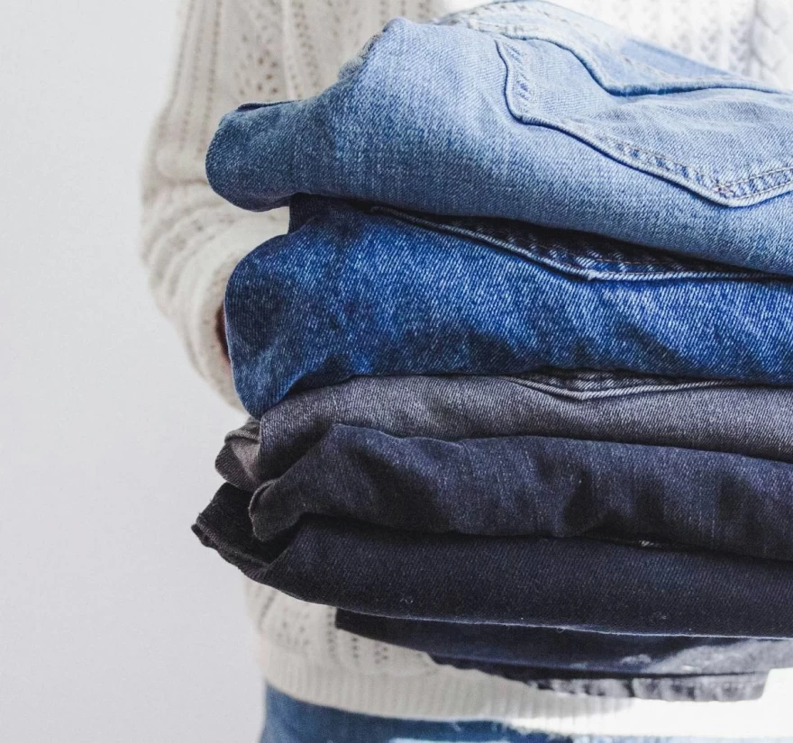 γυναίκα κρατά πολλά jeans στα χέρια της