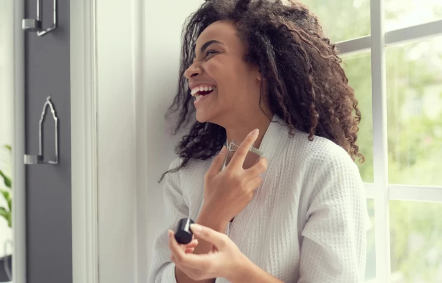 γυναίκα ψεκάζει το άρωμά της πίσω από τα αυτιά