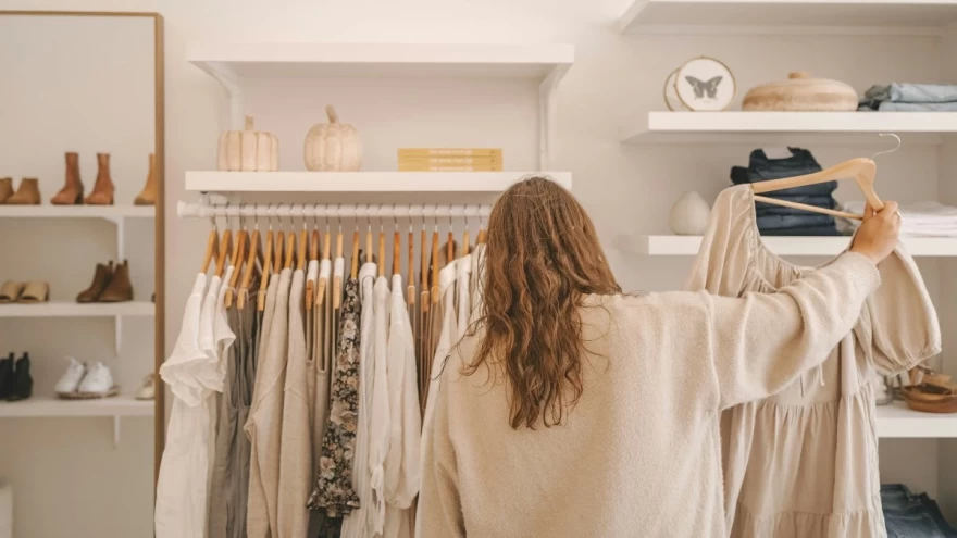 γυναίκα κρατά κρεμάστρα με ρούχα