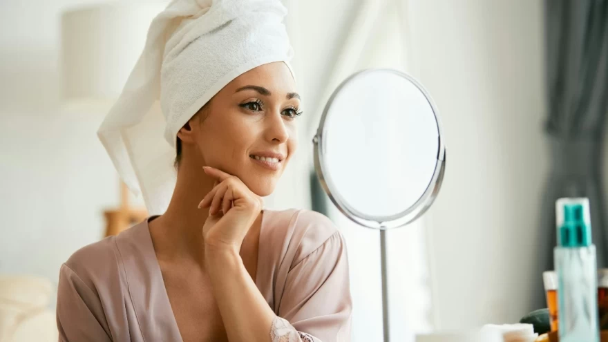 γυναίκα φροντίζει την επιδερμίδα της μπροστά από καθρέφτη