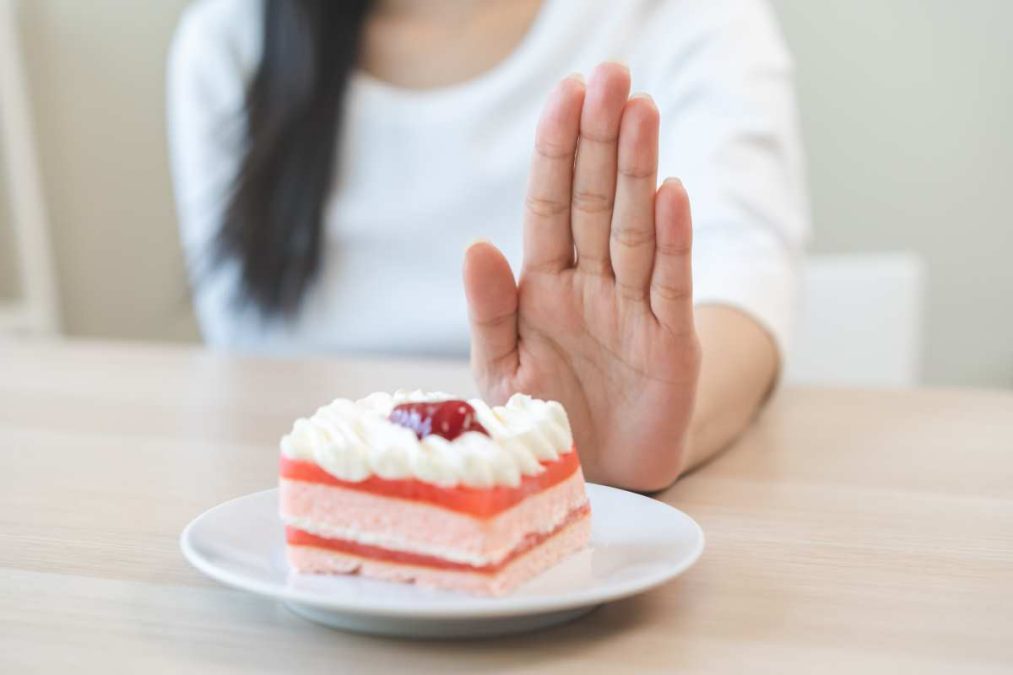 γυναίκα απωθεί πιάτο με γλυκό