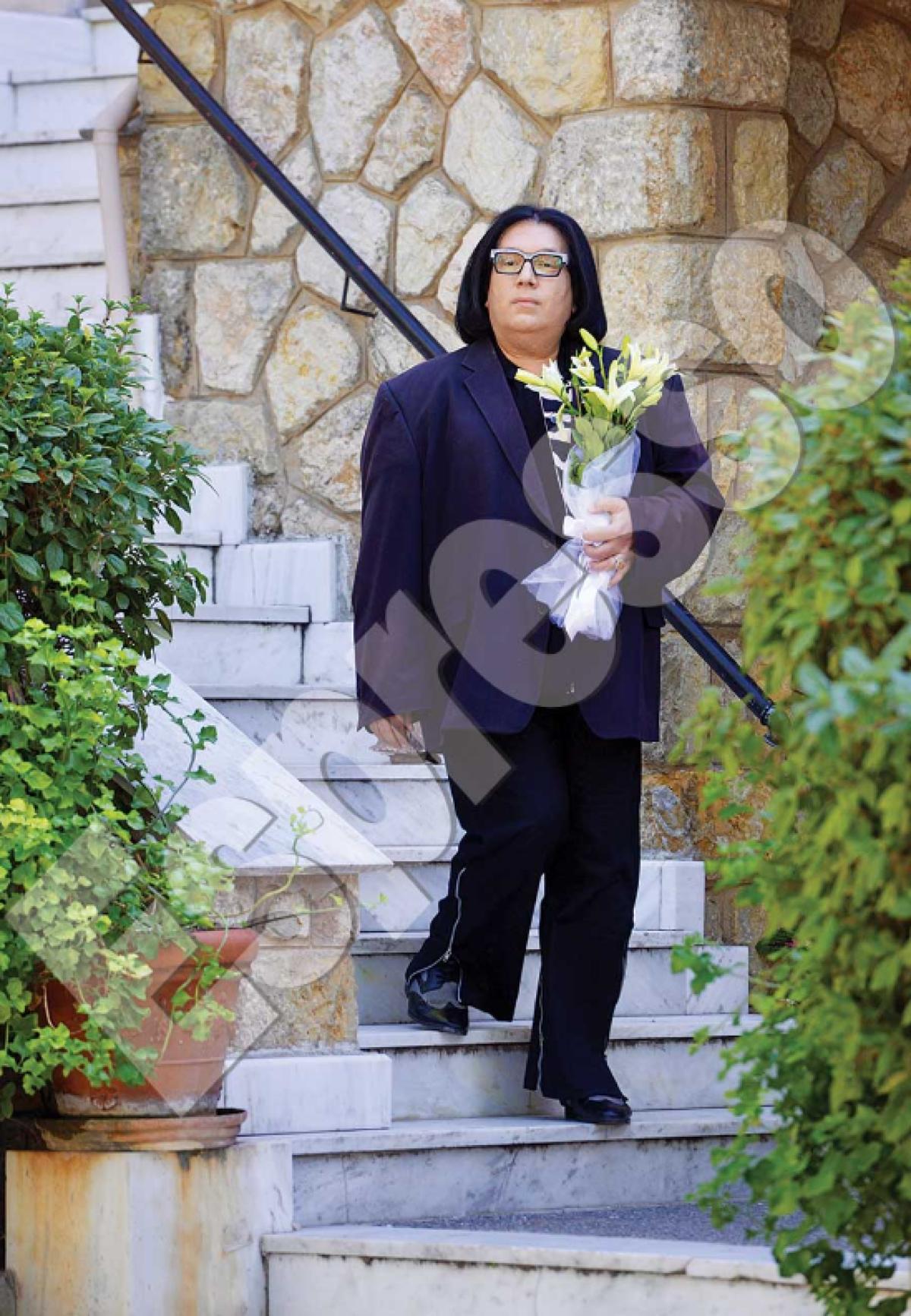 Ο Ανδρέας Ευαγγελόπουλος με navy blue κουστούμι και με λευκά κρίνα στο χέρι την ημέρα του γάμου του