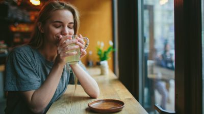 Γυναίκα πίνει ρόφημα τζίντζερ & λεμόνι