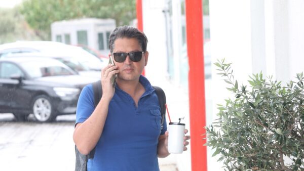 Ο Γιάννης Πουλόπουλος στο δρόμο με το κινητό στο ένα χέρι και καφέ στο άλλο