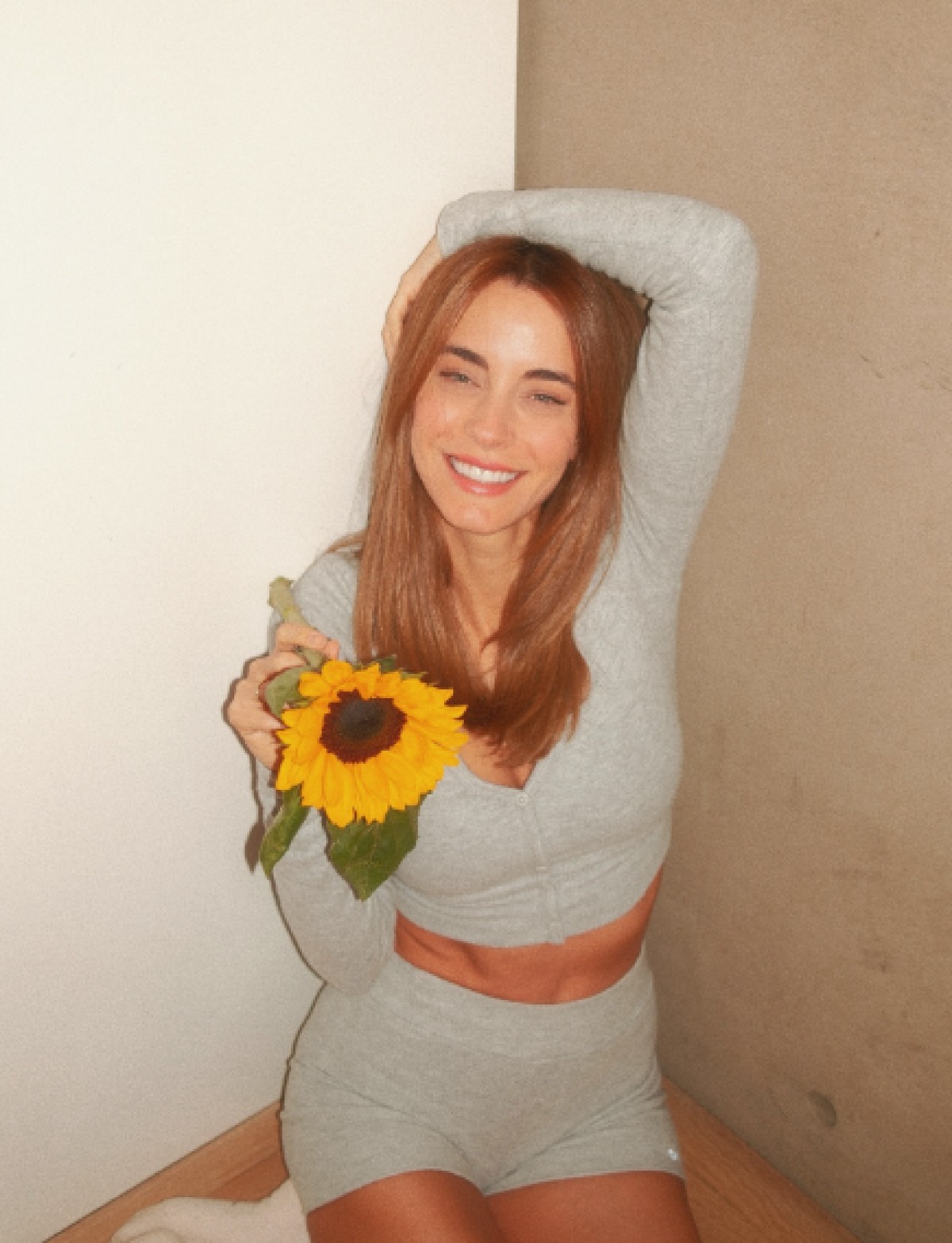 Η Δούκισσα Νομικού με γκρι σετάκι και ένα ηλιοτρόπιο στο χέρι