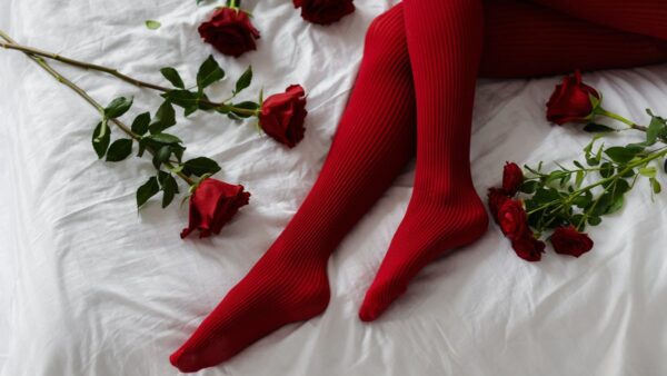 Μια γυναίκα ξαπλωμένη στο κρεβάτι φορώντας κόκκινο καλτσόν