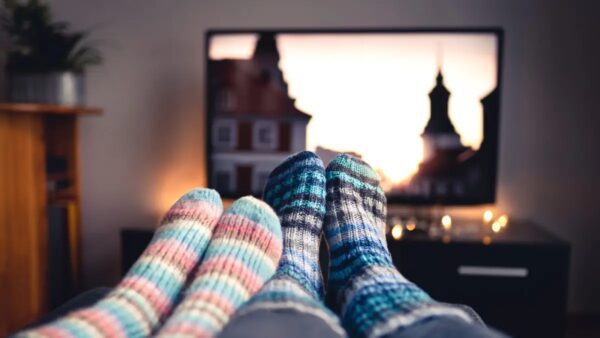 Πόδια με χρωματιστές κάλτσες μπροστά από μία τηλεόραση