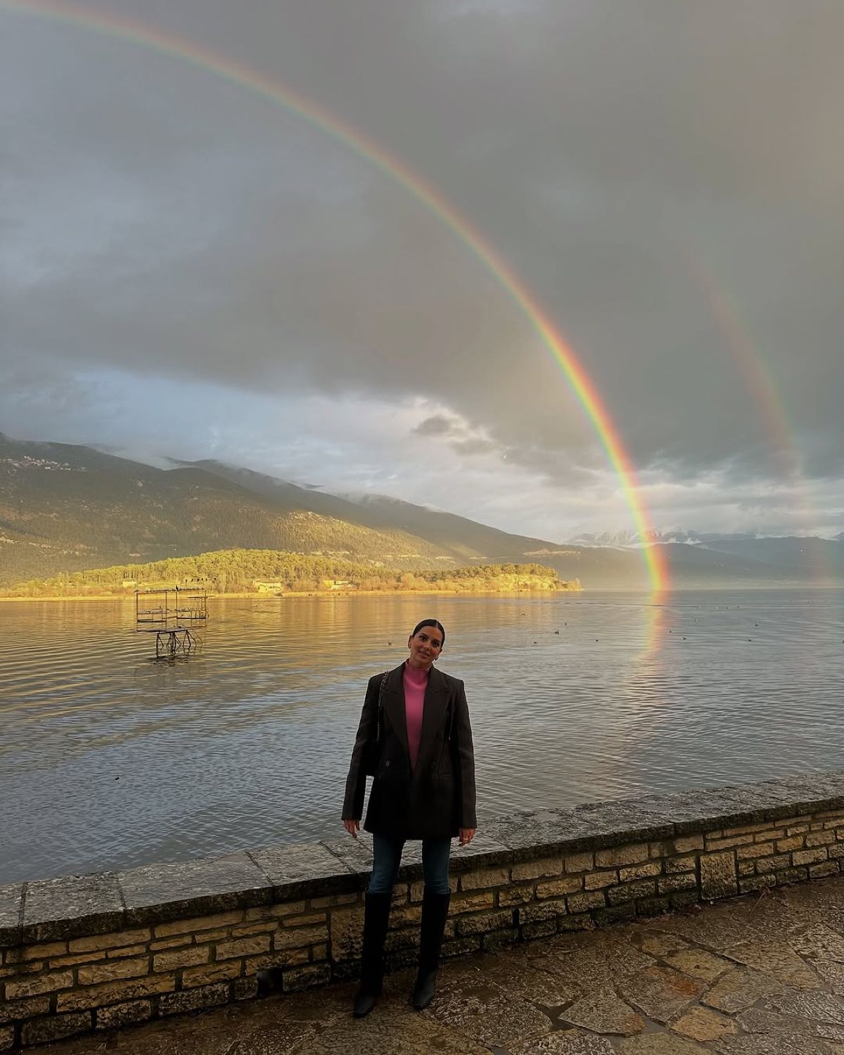 Η Σταματίνα Τσιμτσιλή μπροστά από τη λίμνη Ιωαννίνων με ένα ουράνιο τόξο στον ουαρνό