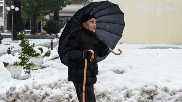 Ένας παππούς με ομπρέλα σε χιονισμένο τοπίο