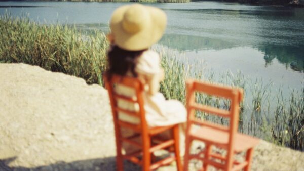 Μια κοπέλα με καπέλο κάθεται σε μια καρέκλα