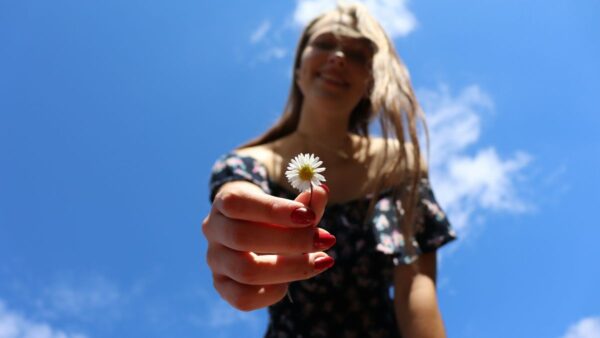 Μια κοπέλα με μαγιό και ένα λουλούδι στο χέρι