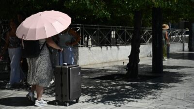 Μια γυναίκα με βαλίτσες και ομπρέλα