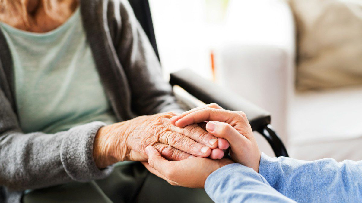 Μια νοσοκόμα κρατά τα χέρια μιας γιαγιάς