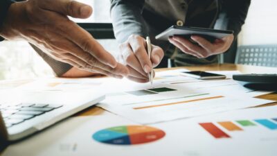 Χαρτιά σε γραφείο και δύο αντρικά χέρια που κρατούν σημειώσεις