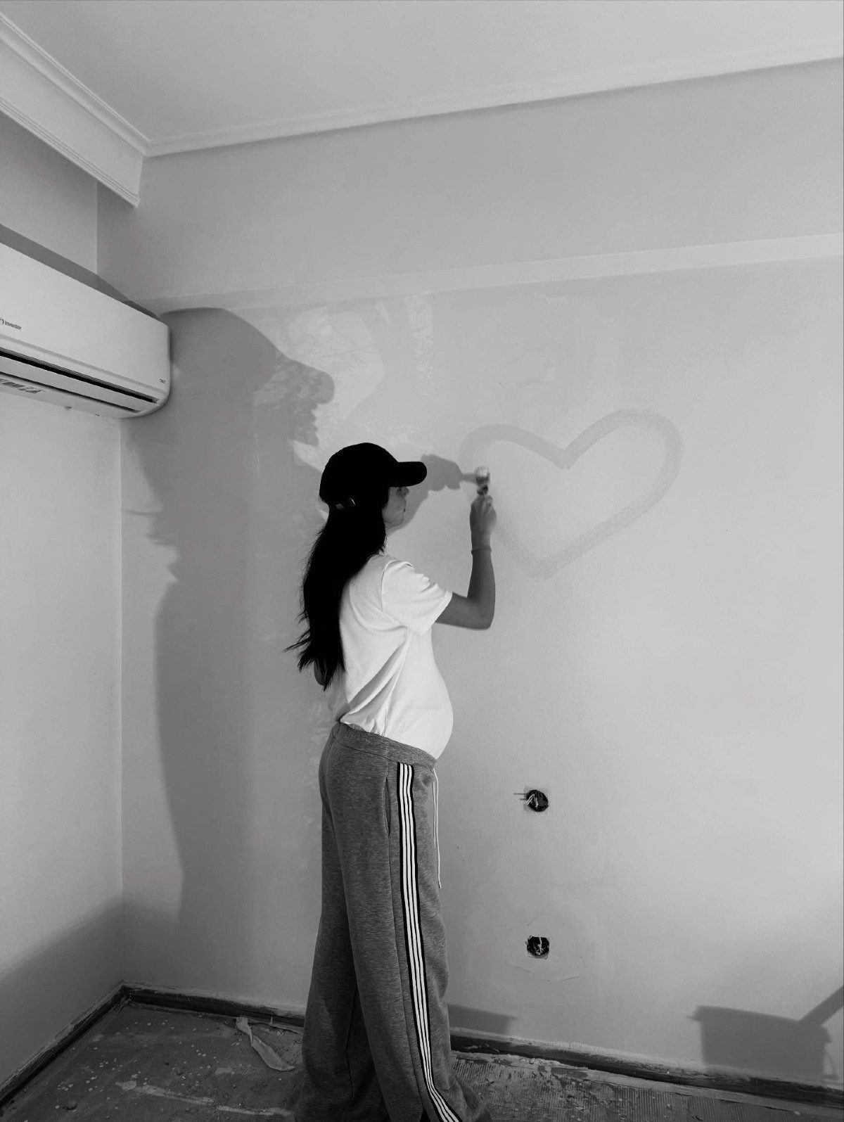 Η Βαλασία Συμιακού, σύντροφος του Νίκου Πολυδερόπουλου, ζωγραφίζει μια καρδιά στον τοίχο του βρεφικού δωματίου, στο σπίτι του ζευγαριού.