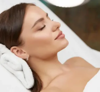 Γυναίκα ξαπλωμένη σε χώρο περιποίησης με κλειστά μάτια και χαλαρή έκφραση