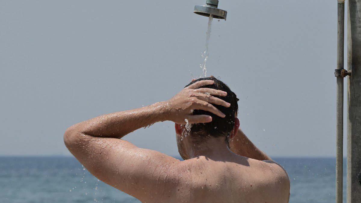 ένας άνδρας στην παραλία κάνει ντουζ